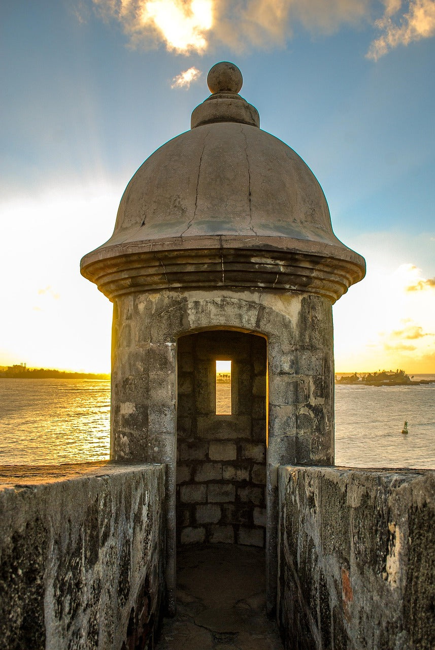 Scenic view of a historic watchtower at sunset near the ocean in Puerto Rico, showcasing handcrafted Puerto Rican gifts.