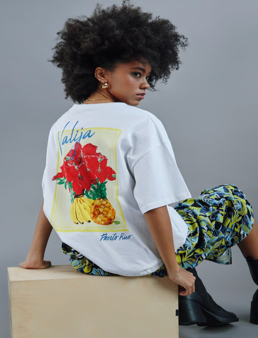 Stylish model wearing a Valija x Boricua souvenir shirt featuring tropical floral designs and island vibes