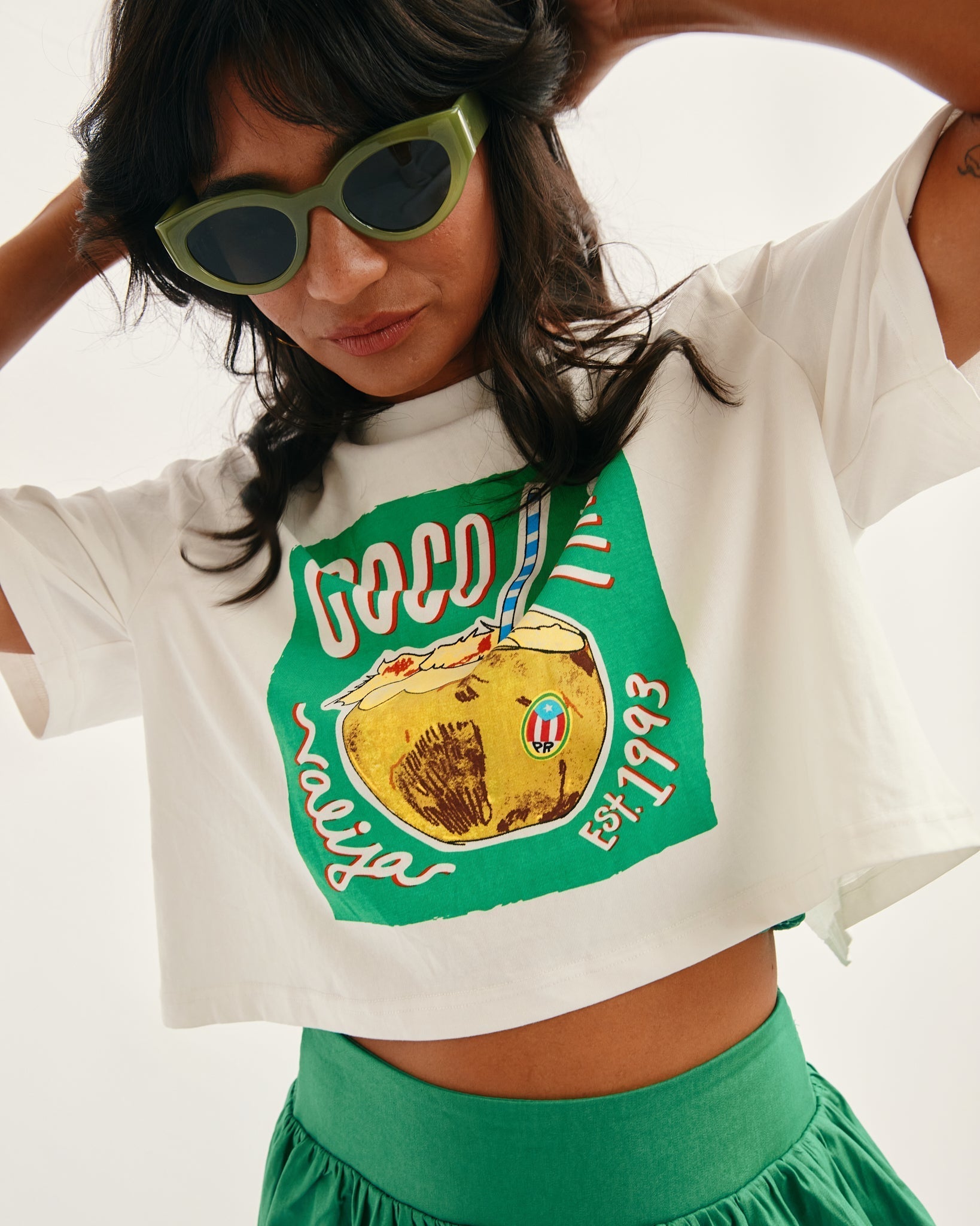 Stylish model wearing a Valija x Boricua souvenir shirt featuring tropical floral designs and island vibes