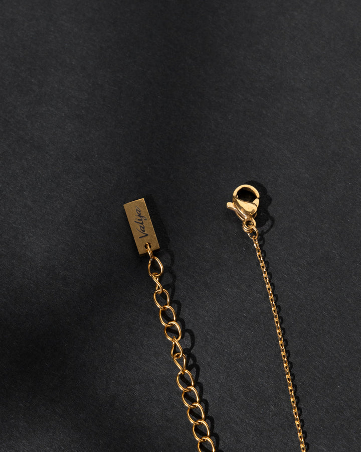 Close-up of Valija 18K gold plated palm necklace chain with lobster clasp and branding tag