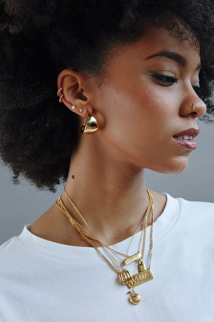 Valija 18k gold plated plantain pendant layered with delicate gold chains on model wearing earrings