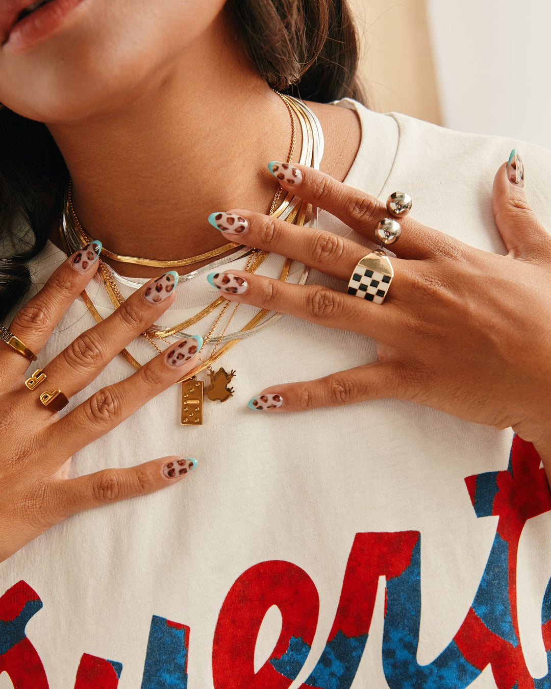 Layered jewelry display featuring an 18K plated Coquí necklace among gold accessories