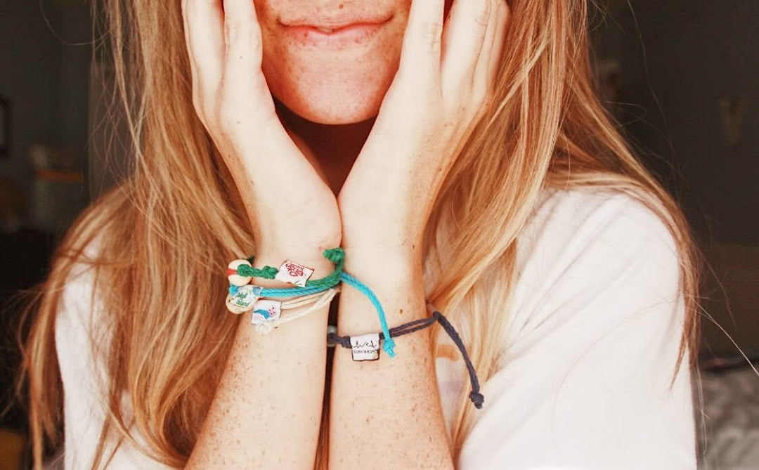 Close-up of a person wearing multiple bracelets including an alien friendship bracelet handmade