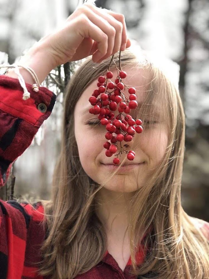 Child wearing an autism puzzle piece bracelet while holding red berries outdoors