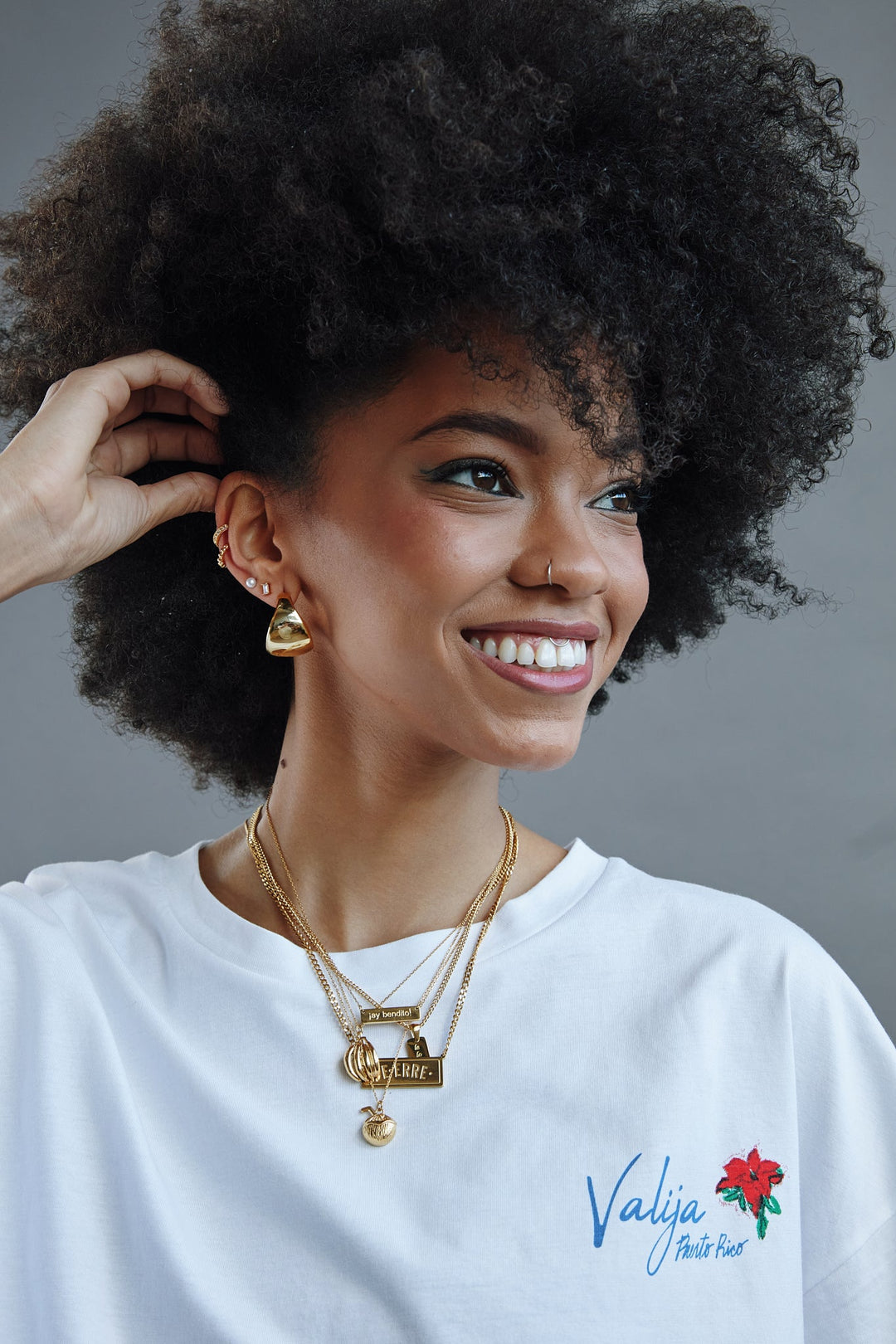 Ay Bendito necklace worn by a model with curly hair, styled with layered gold chains