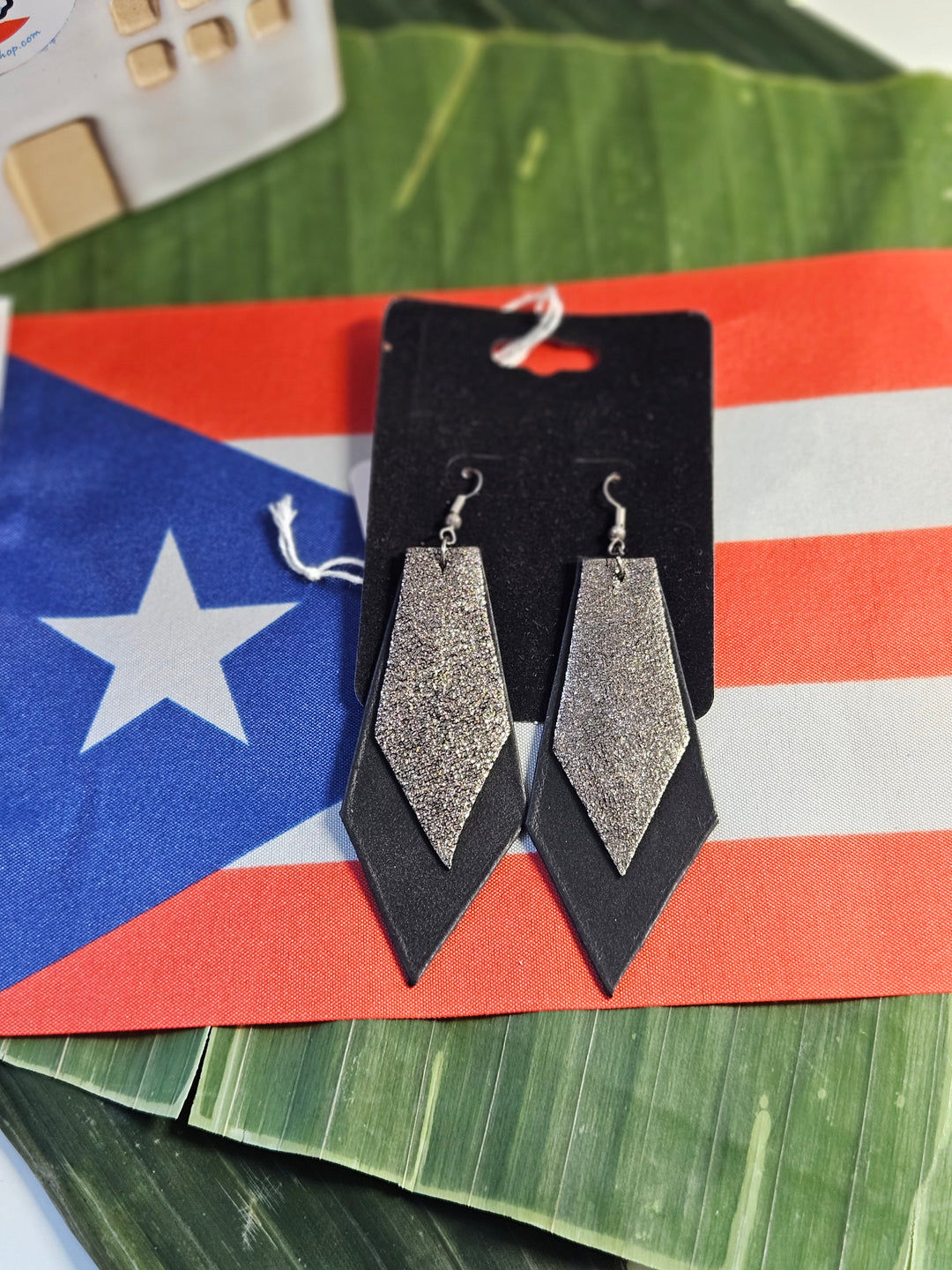 Atelierry by Arlene Irizarry black and silver statement earrings on a Puerto Rican flag background