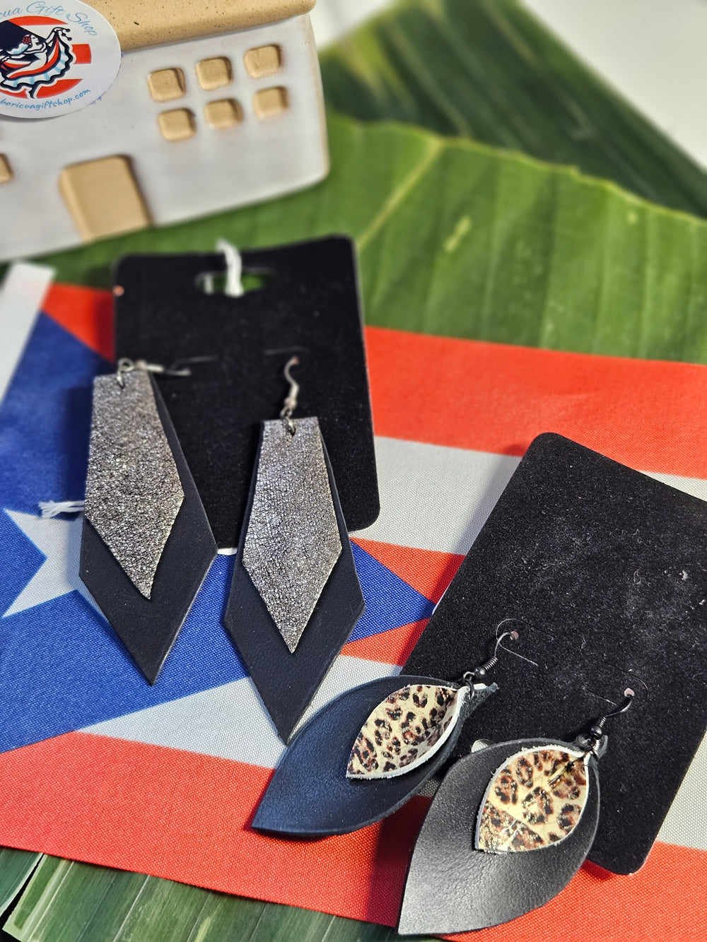 Black and silver statement earrings in various designs, showcased with a Puerto Rican flag backdrop