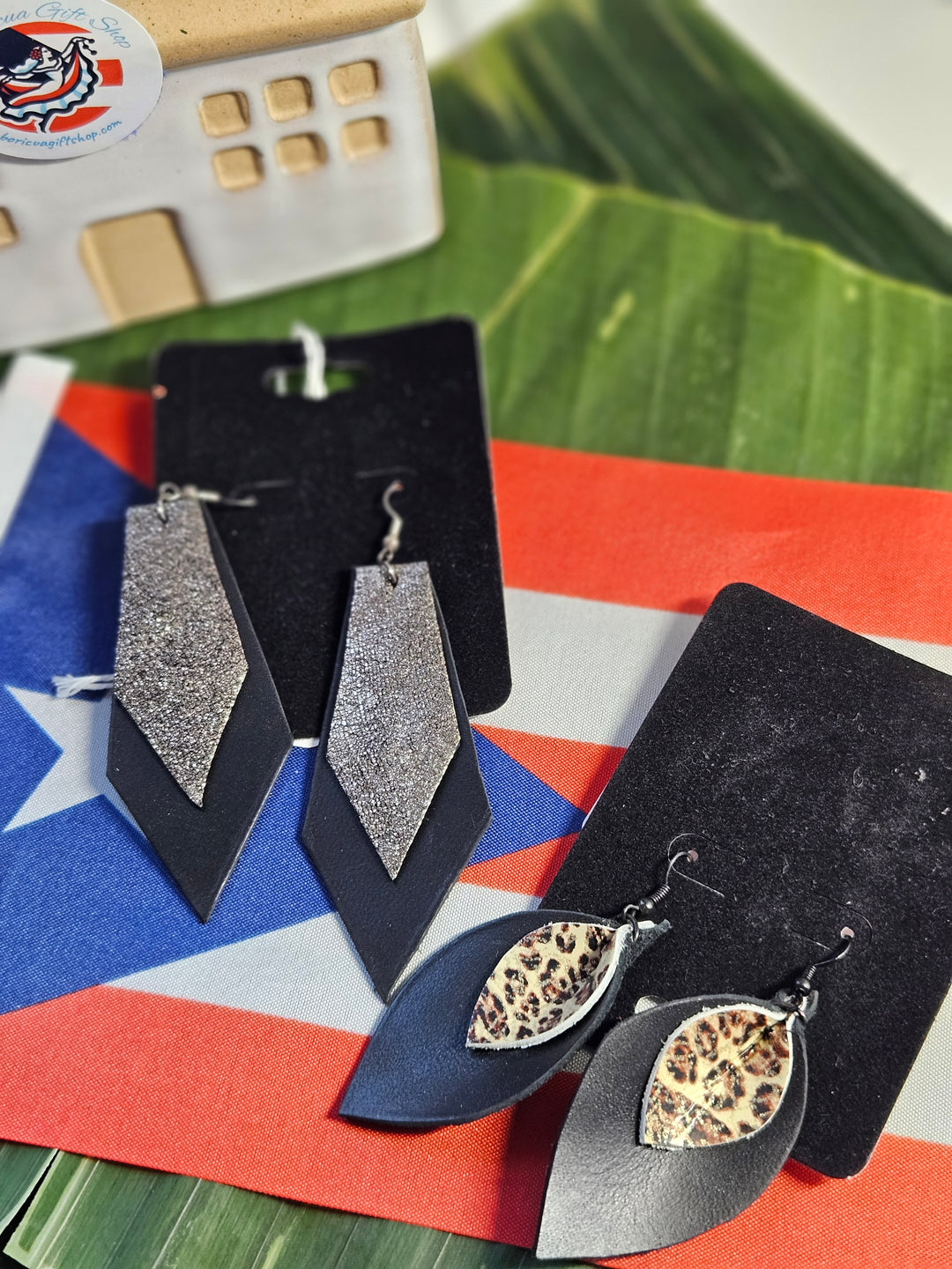 Black and silver statement earrings in various designs, showcased with a Puerto Rican flag backdrop
