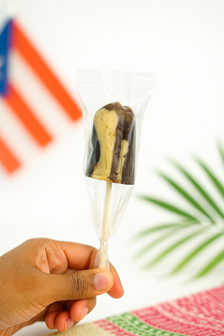 Hand holding a coffee and milk lollipop from Puerto Rico in clear packaging against a colorful background