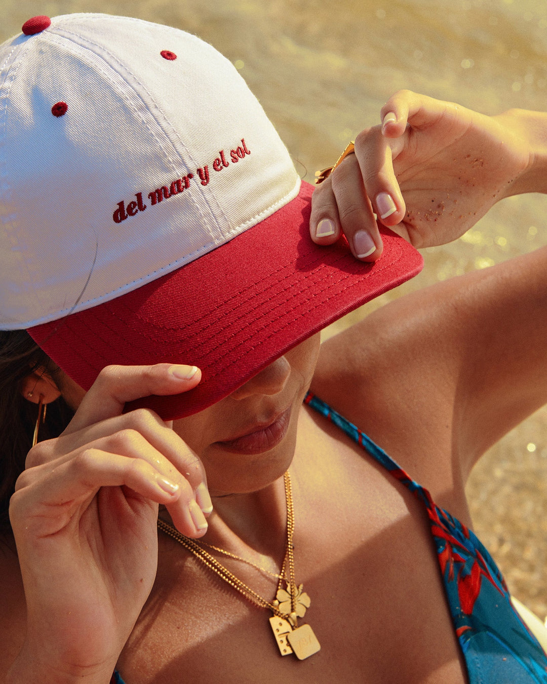 Woman wearing Del Mar Y El Sol souvenir cap with a red brim at the beach
