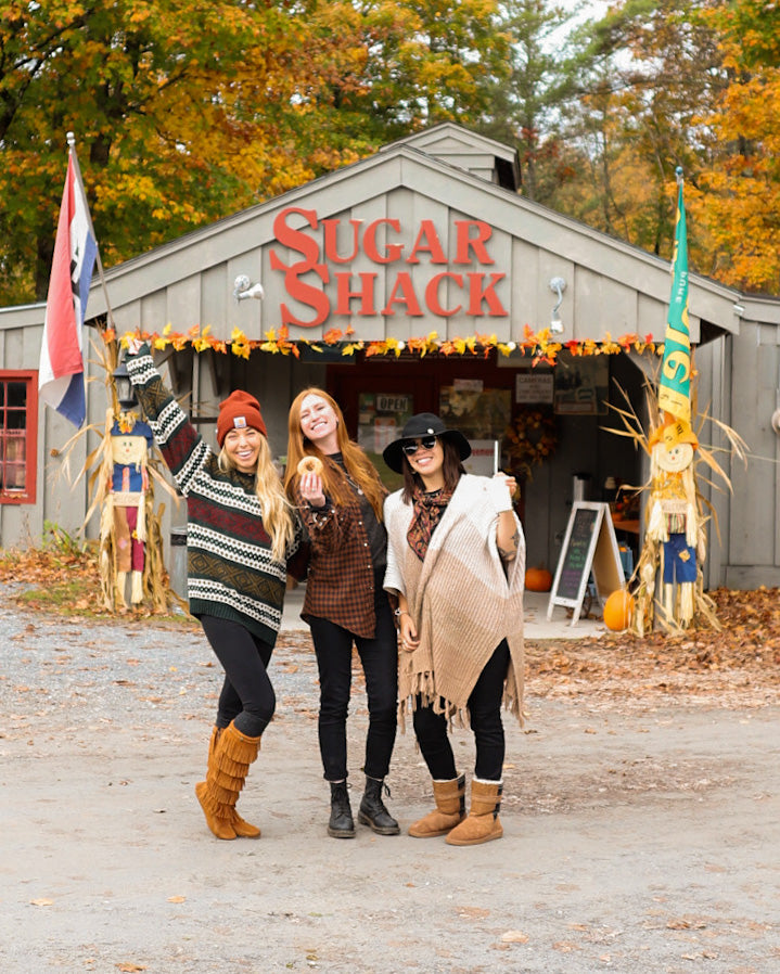 Women wearing cozy outfits posing in front of Sugar Shack, perfect for handmade Christmas Santa gift shopping