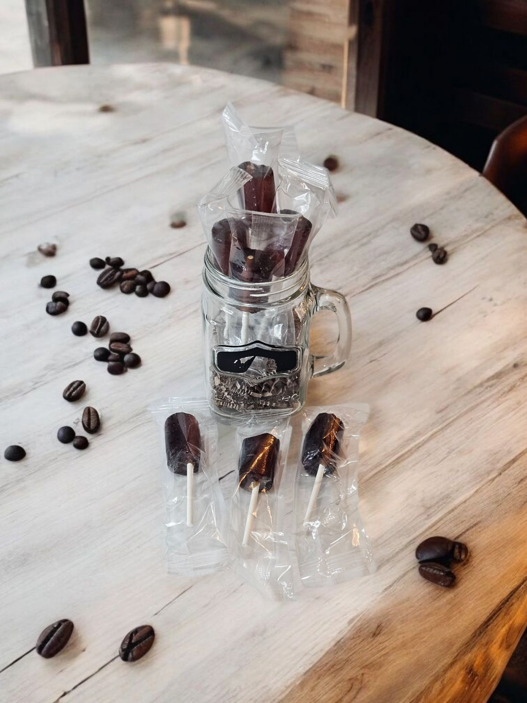 Jar of handmade coffee candy lollipops displayed with coffee beans on a wooden table