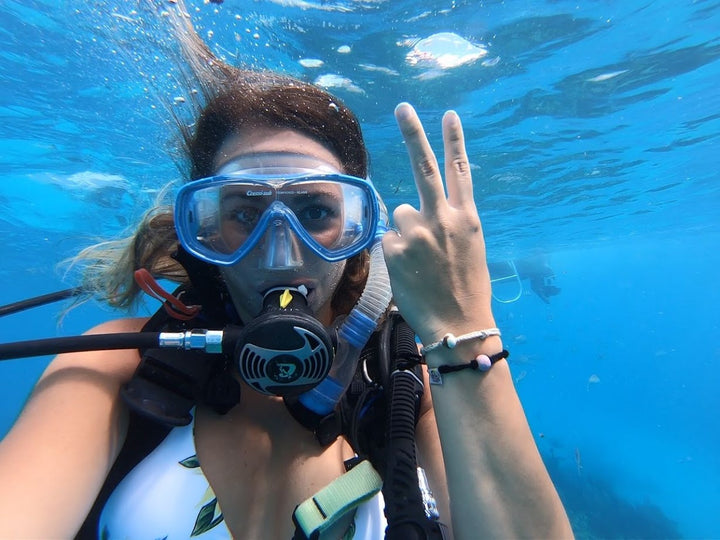 Woman scuba diving underwater showing a handmade Puerto Rican encouragement bracelet on her wrist