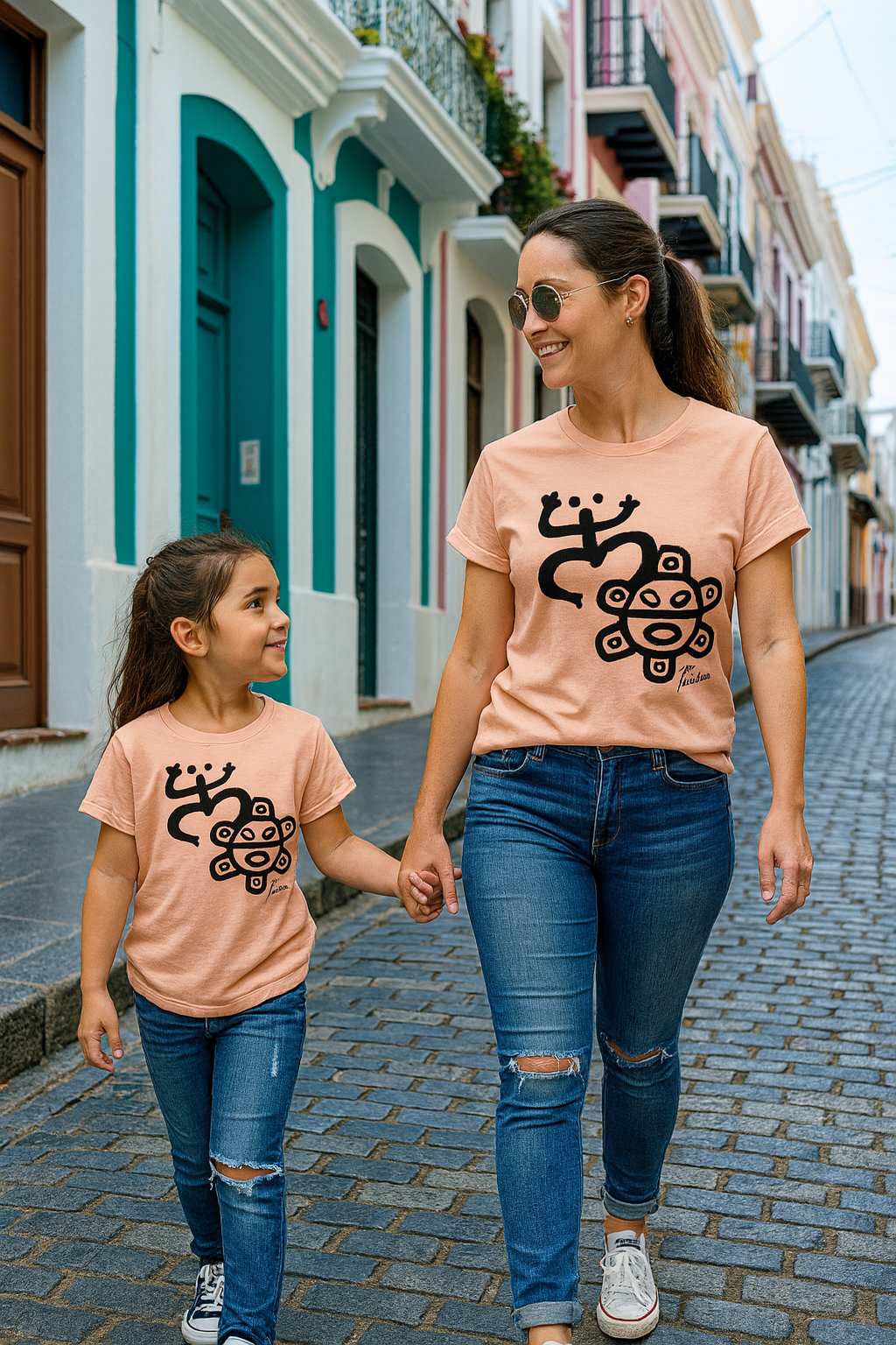 Taino symbol shirt mother and daughter matching peach tees walking in colorful Puerto Rico street