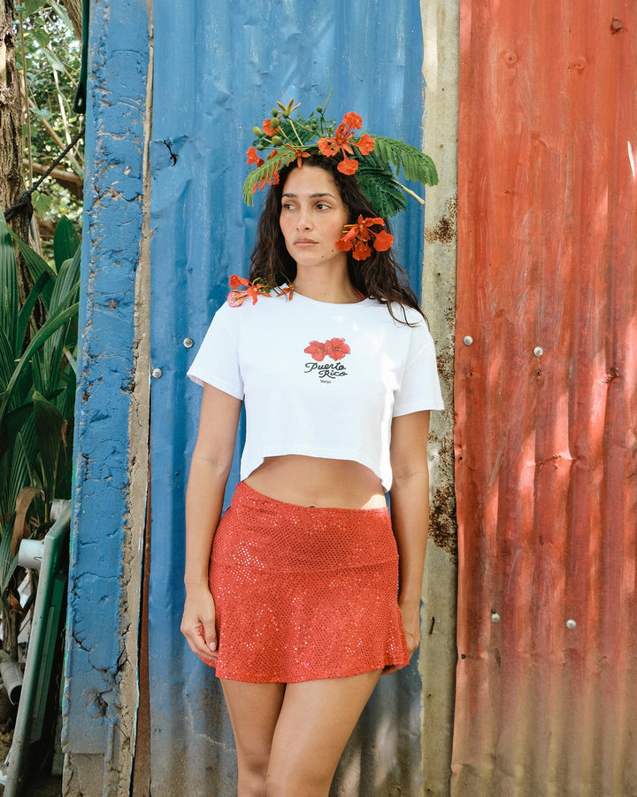 La Rincon Maga top for women in white with floral design, styled with a red skirt and tropical backdrop