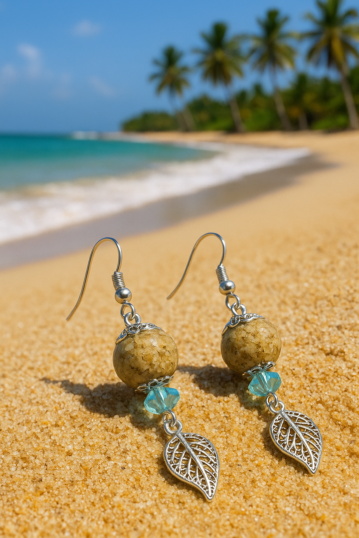 Lagunarte sand and crystal earrings with silver leaf charms on sandy beach background