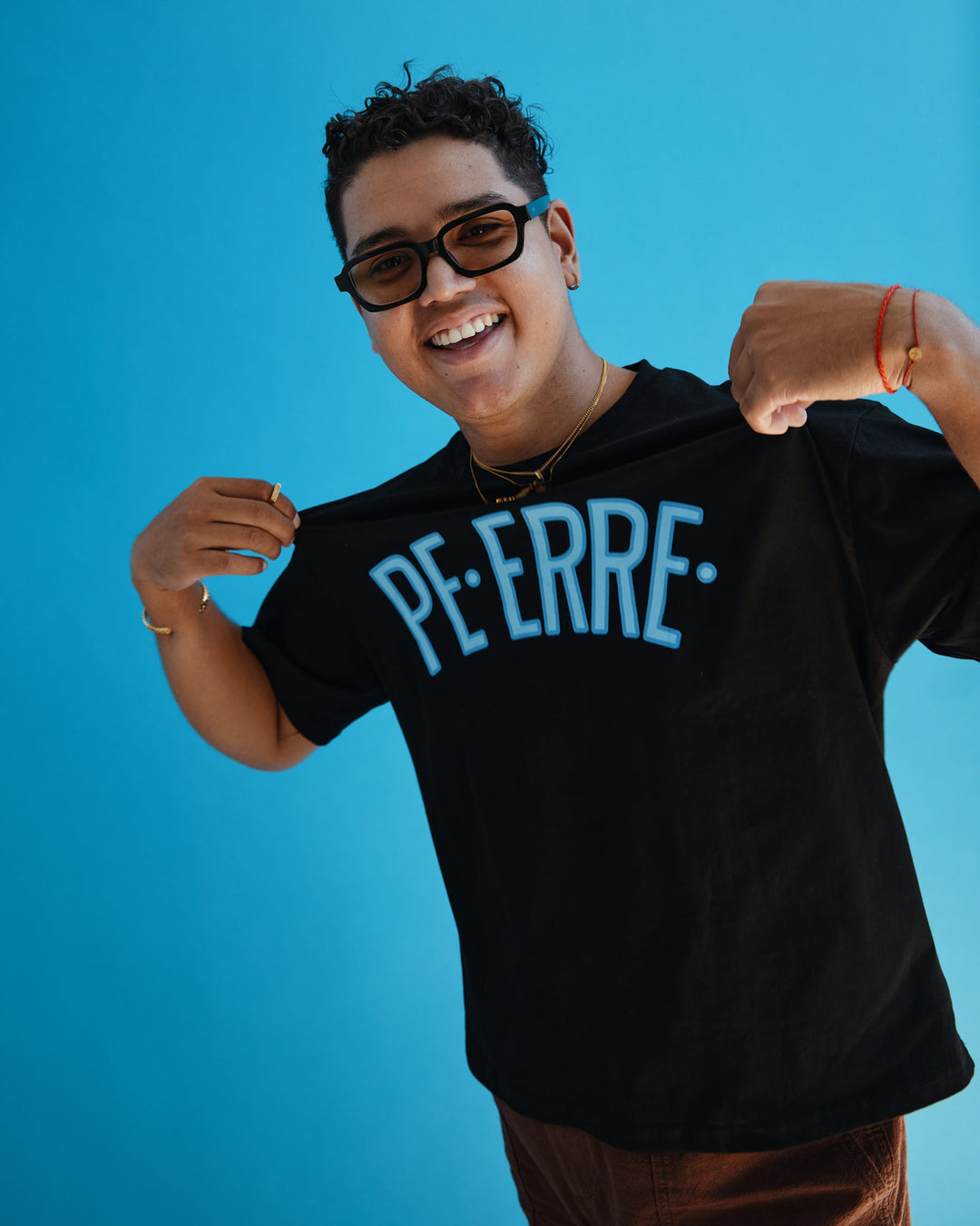 Model wearing a black PE ERRE t-shirt with a bold blue graphic design on a bright background