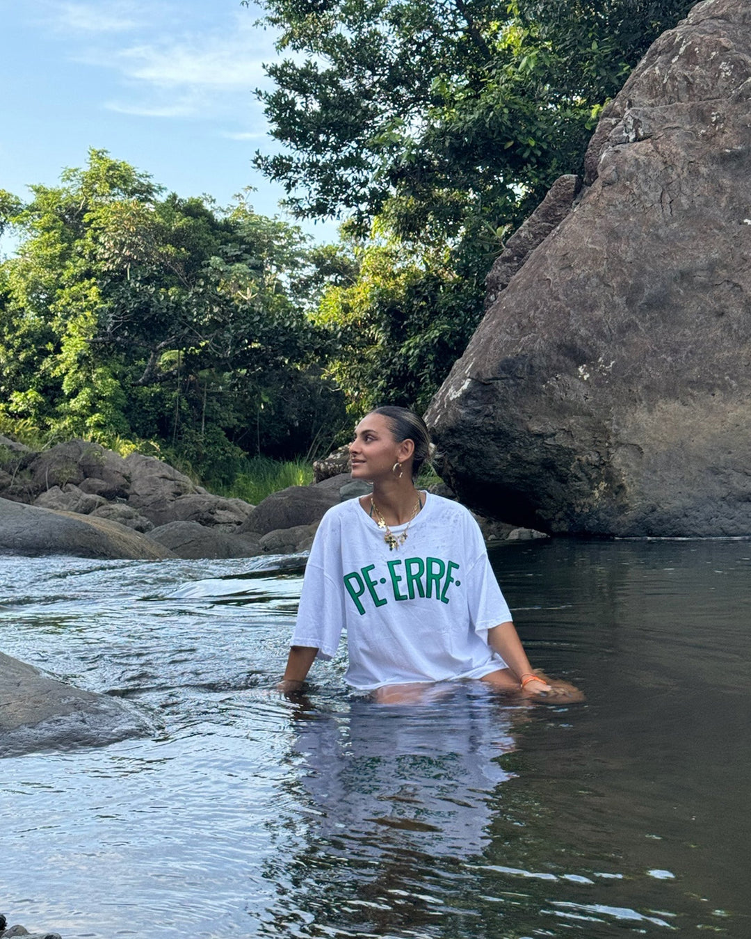Model wearing PE ERRE t-shirt while wading in a scenic river surrounded by nature