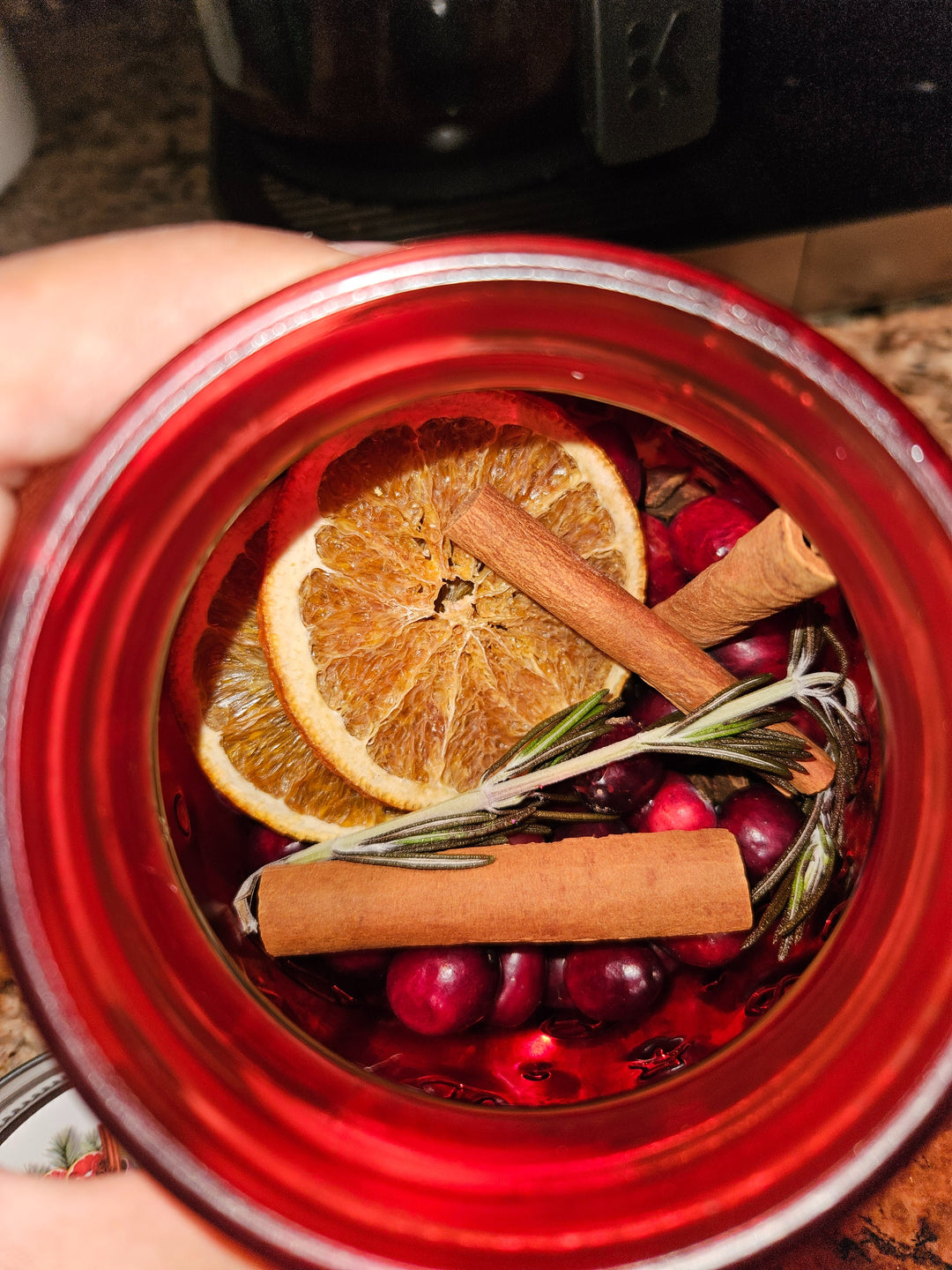 Puerto Rican holiday simmer pot jar filled with orange slices, cinnamon sticks, cranberries, and herbs
