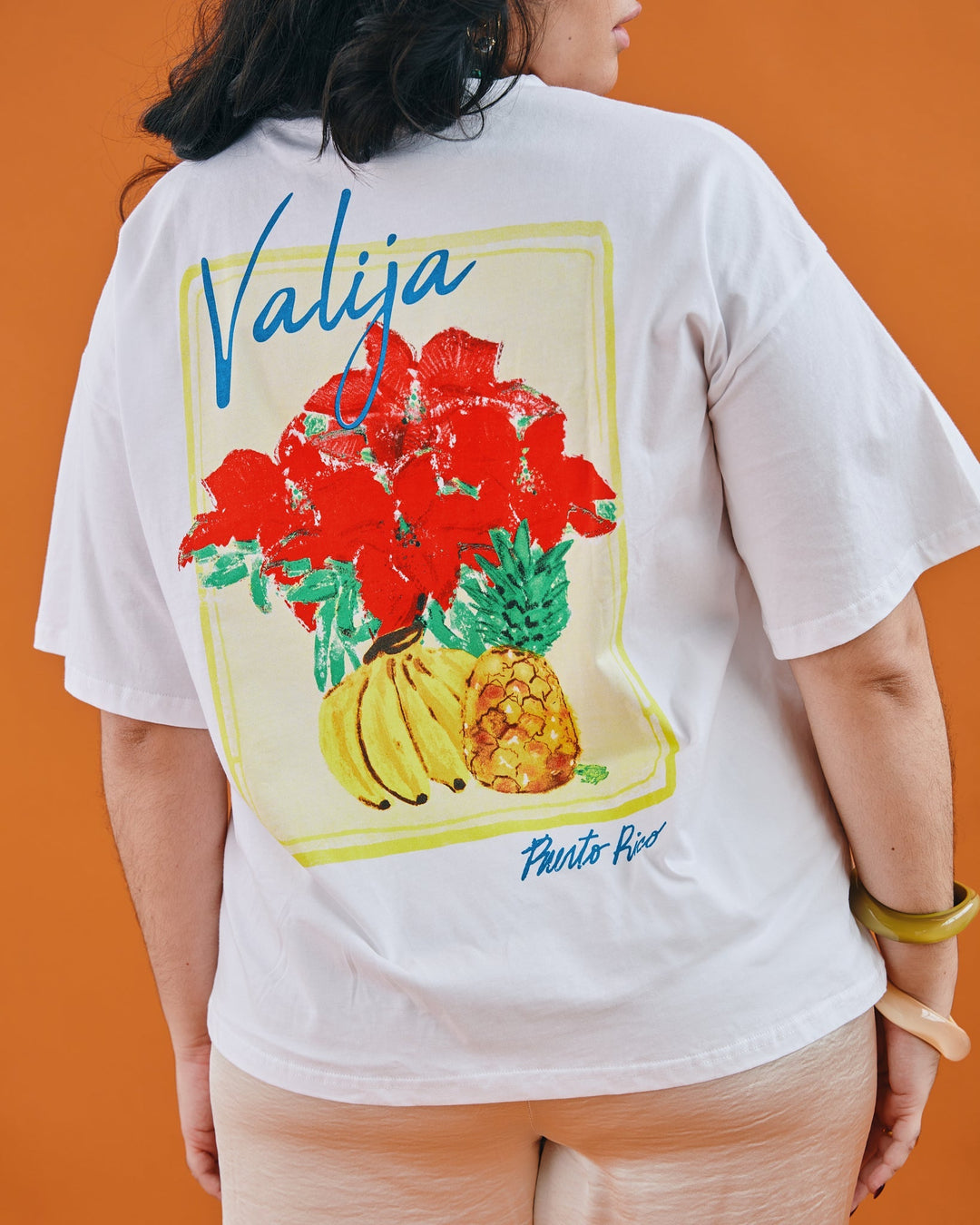 Valija abuelita graphic top featuring colorful flowers and tropical fruits on a white tee