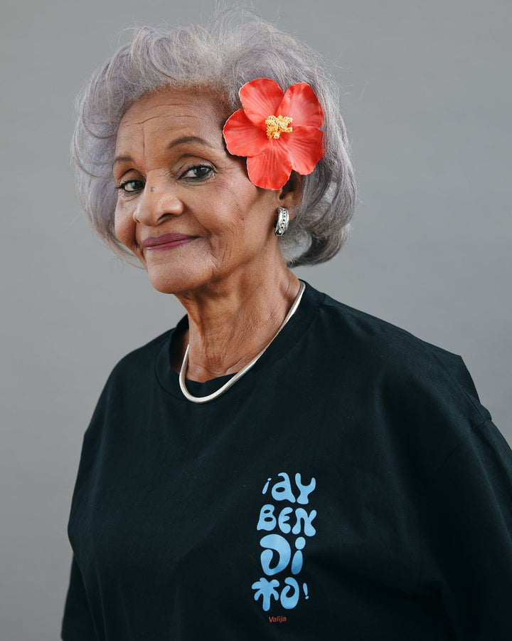 Valija Ay Bendito graphic T-shirt in black displayed on a model with gray hair and floral accessory