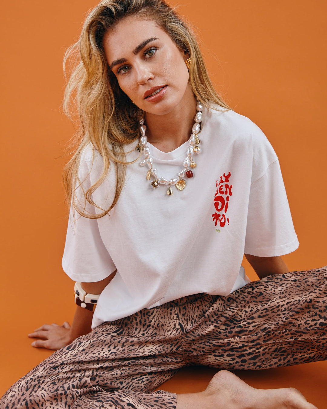 Ay Bendito graphic T-shirt in white featuring bold red lettering, styled with patterned pants