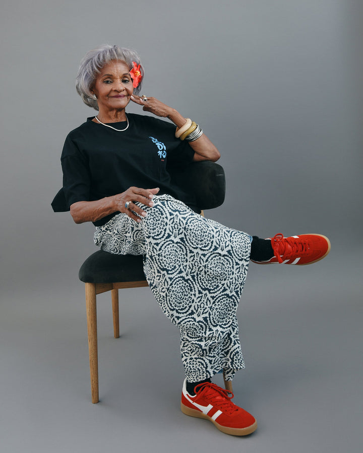 Valija Ay Bendito graphic T-shirt styled with patterned pants and red sneakers for a trendy look