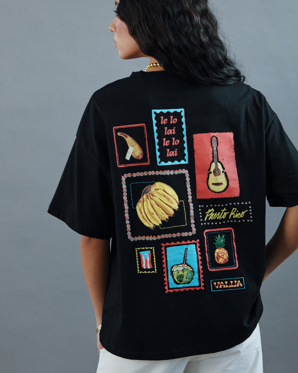 Valija Parranda graphic t-shirt featuring colorful tropical designs and instruments on a black background